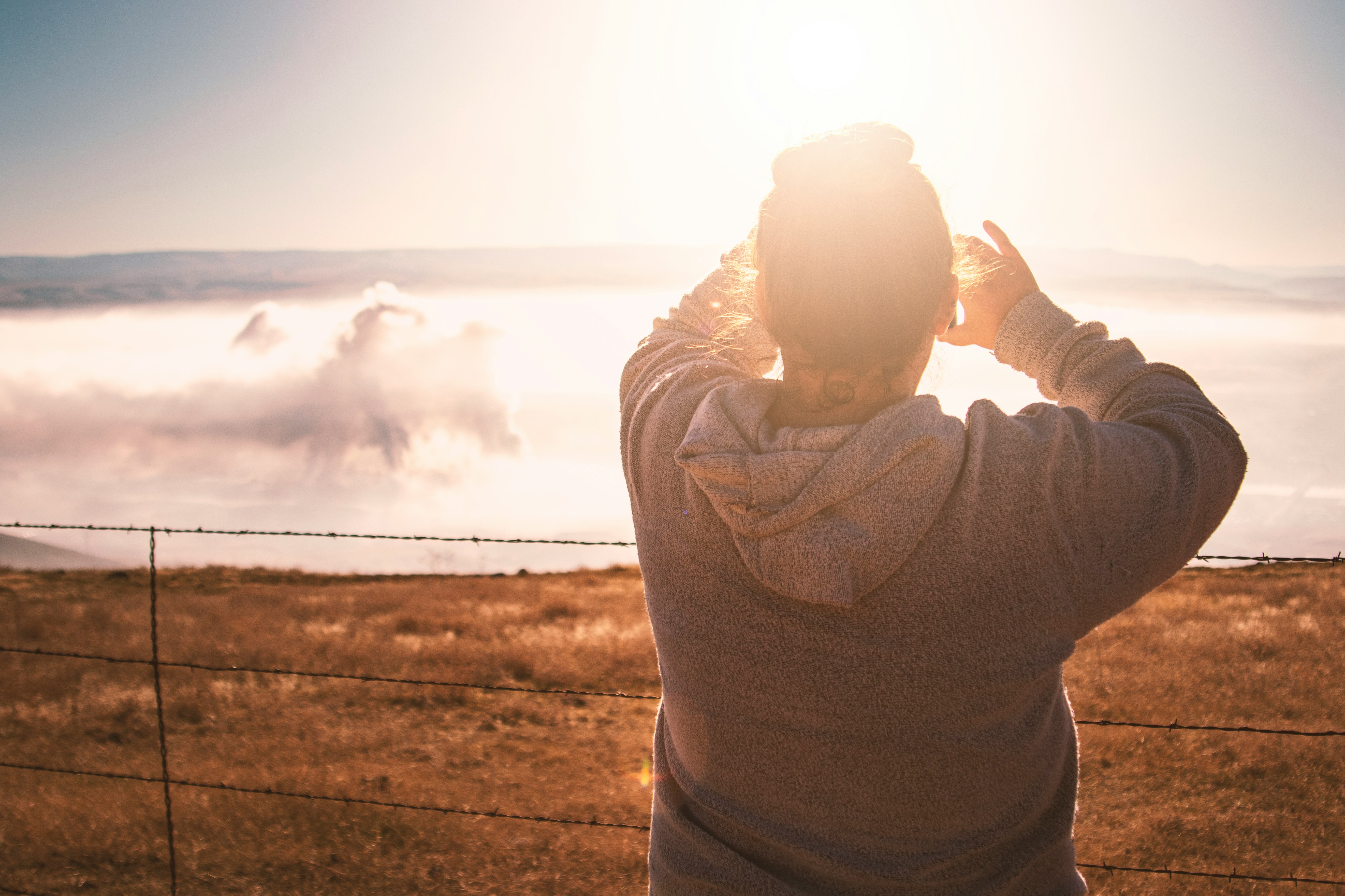 woman in gray sweater standing on brown field during daytime